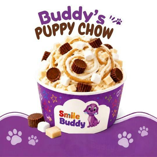 A cup of Smile Buddy Puppy Chow ice cream topped with peanut butter swirl, peanut butter cups, marshmallows and fudge pieces